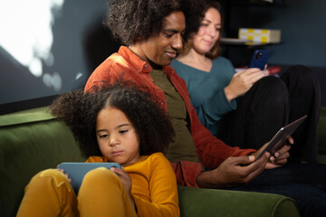 Family at home all using digital devices for entertainment in the evening