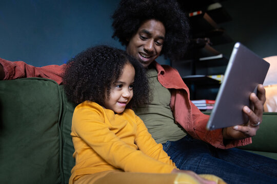 Father reading daughter a story using a digital tablet