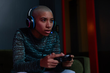 Young adult female gamer concentrating at home at night