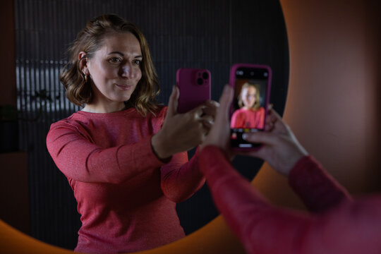 Woman taking a selfie in bathroom mirror getting ready to go out with friends