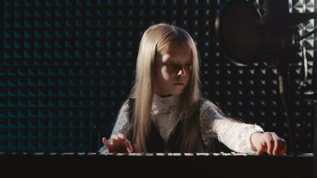 Child fine-tunes sound of digital instrument. Girl adeptly sets up electric piano infusing studio with artistic touch. Student demonstrates musical prowess