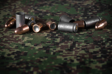 Demounted handgun bullet shell sets in bulk on green camouflage military cloth textile background
