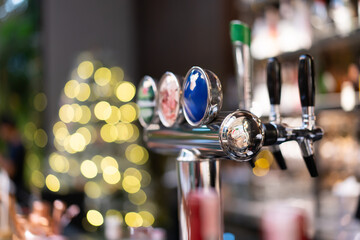 A beer dispenser sits on a shelf in front of a vintage bar with a beautiful bokeh light background. Alcoholic drinks in pubs for weekend parties