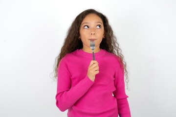 Photo of dreamy Beautiful teen girl wearing pink sweater over white background lick fork look empty space