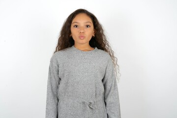 Shot of pleasant looking Beautiful teen girl wearing  grey dress over white background,  pouts...