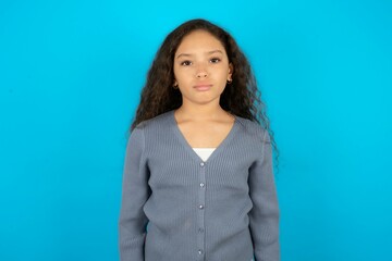 Displeased upset Beautiful teen girl wearing blue jacket over blue background frowns face as going...