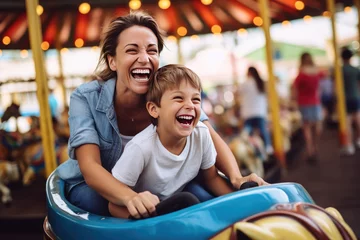 Foto auf Acrylglas Joyful mother and son enjoying a fun summer, riding a bumper car at an amusement park © Kien