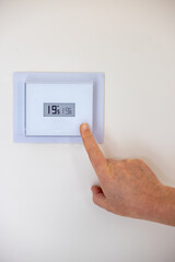Person adjusting the temperature of their thermostat - 695295710