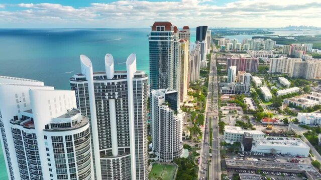 View from above of luxurious highrise hotels and condos on Atlantic ocean shore in Sunny Isles Beach city. Urban street with busy traffic. American tourism infrastructure in southern Florida