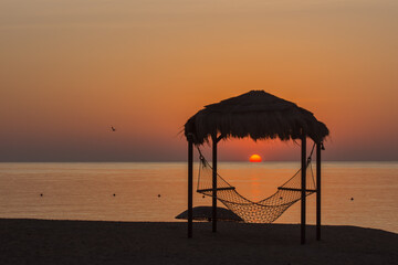 hammock with reed roof at the beach during sunrise