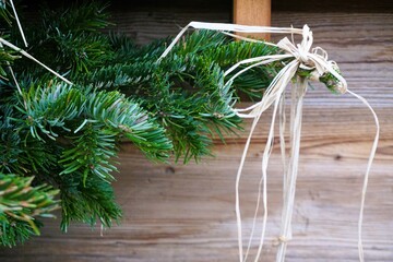 Weihnachtsdekoration mit Tannenbaum und weißer Schleife aus Bast über Holzboden