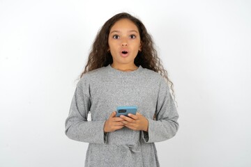 Shocked Beautiful teenager girl  opens mouth hold phone reading advert unbelievable big shopping...