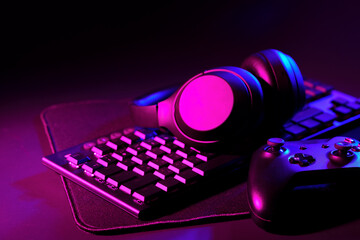 Headphones, joystick and computer keyboard on black table