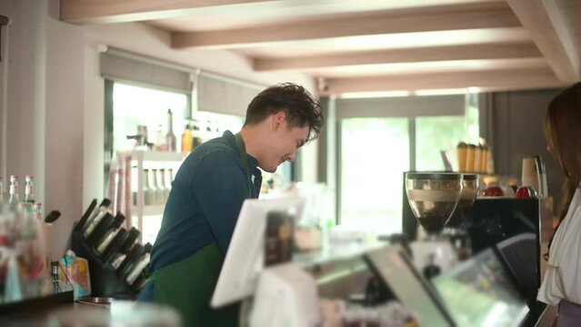 Young Asian service minded barista  with customer in coffee shop