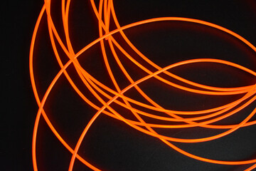 Unusual glowing background of chaotically stacked thin light wires, red glowing tourniquet, illuminated, thin wire placed on a thin background.