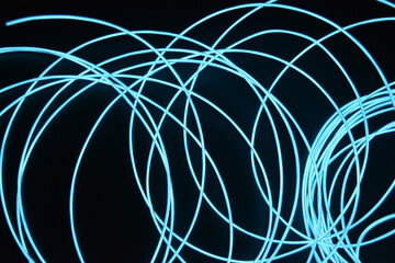 A glowing chaos of thin light wires. An unusual, unique glowing background of chaotically stacked thin wires, celestial, blue, light blue, neon harness, illuminated wire, thin wire.