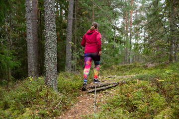 Athletic middle-aged woman running along a path in a nature park in the forest in Finland