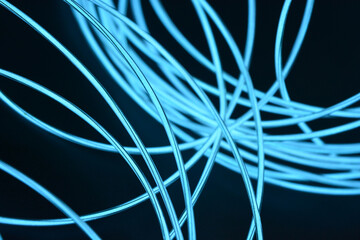 A glowing chaos of thin light wires. An unusual, unique glowing background of chaotically stacked thin wires, celestial, blue, light blue, neon harness, illuminated wire, thin wire.
