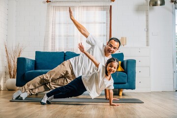 At home a father and his daughter enjoy a joyful yoga session focusing on togetherness happiness...