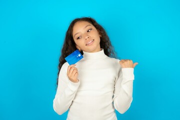 Young beautiful teen girl hold credit card point empty space