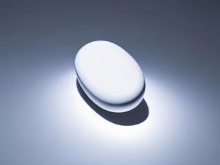 Un primer plano de una sola píldora blanca, iluminada por una luz brillante sobre un fondo blanco crudo