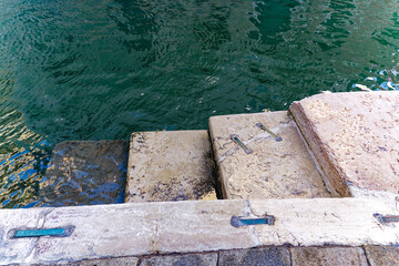 Close-up of stone steps of stairway at canal at the old town of Italian City of Venice on a sunny summer day. Photo taken August 6th, 2023, Venice, Italy.