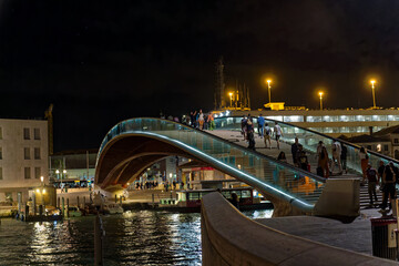 City of Italian City of Venice with pedestrians crossing Bridge of Constitution on a dark summer night. Photo taken August 6th, 2023, Venice, Italy.