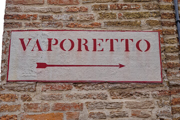 Close-up of brick wall with direction sign to vaporetto passenger ship of Venice on a cloudy summer...