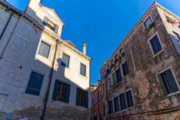 Fototapeta na wymiar Scenic view of alley with colorful weathered facades of historic houses at City of Venice on a sunny summer day. Photo taken August 7th, 2023, Venice, Italy.