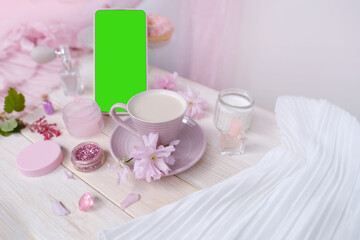 coffee cup, smartphone with blank green screen, cosmetics, perfume in spray bottle, donut, sakura flowers, good morning concept, coffee time in boudoir, female life