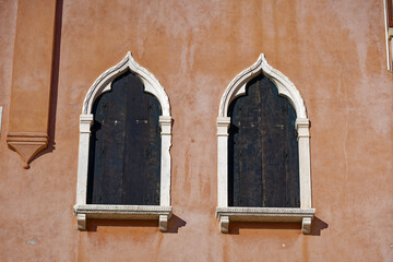 Scenic view of cityscape with close-up of red facade of historic house with green wooden shutters at City of Venice on a sunny summer day. Photo taken August 6th, 2023, Venice, Italy.