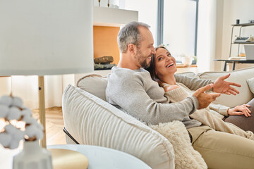 happy couple talking on comfortable couch in modern living room at home, child-free lifestyle