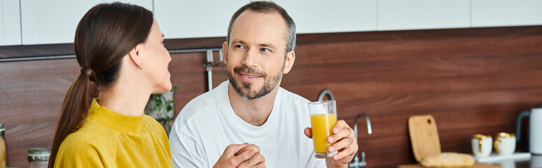 cheerful child-free couple holding hands during breakfast in modern kitchen, horizontal banner