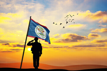 Silhouette of a soldier with the Belize flag stands against the background of a sunset or sunrise....