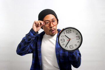 An excited young Asian man, dressed in a beanie hat and casual shirt, enthusiastically holds a...