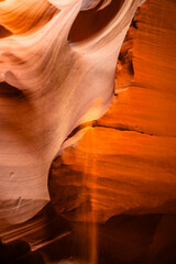 Image capturée dans le majestueux Antelope Canyon aux États-Unis, baignée d'une lumière orangée alors que les rayons du soleil filtrent à travers les fissures rocheuses.