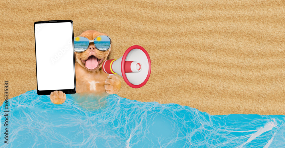 Poster Happy Mastiff mastiff puppy lying at sunny beach and showing big smartphone with white blank screen in it paw and screaming into a megaphone. Empty space for text