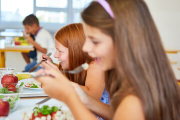Happy girl having meal with friend in school