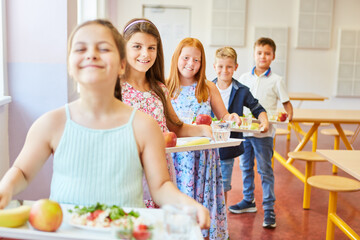 Smiling students standing in line holding food trays