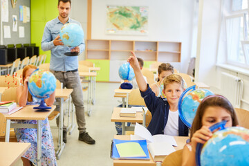 Students studying with globes with teacher in class