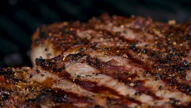 Grilled meat steak on stainless grill depot with flames on dark background. Food and cuisine concept.