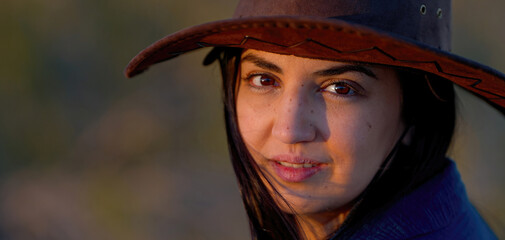Portrait shot of a young cowgirl wearing a cowboy hat posing for the camera - travel photography