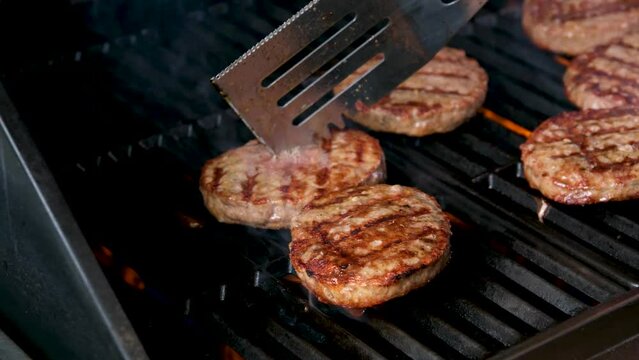 Cooking burgers on a hot grill with a flame Beef cutlets cooked on a barbecue grill.Cooking beef and pork patty for party.
