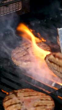 Cooking burgers on a hot grill with a flame Beef cutlets cooked on a barbecue grill.Cooking beef and pork patty for party.