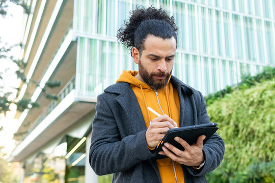 Focused man using tablet outdoors in urban setting