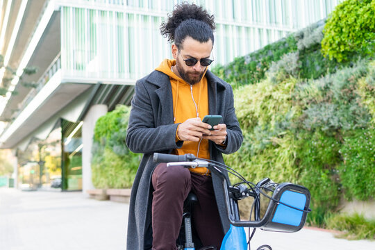 Stylish Man Using Smartphone While Leaning On Bike Outdoors