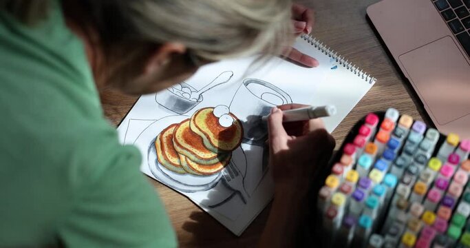 Woman draws drawing of food cup and pancakes. Conscious creativity and home hobbies