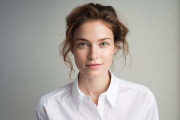 Fototapeta premium Portrait of a tender woman in her 30s wearing a classic white shirt against a white background. AI Generation