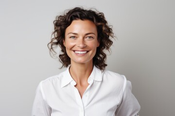 Fototapeta premium Portrait of a smiling woman in her 40s wearing a simple cotton shirt against a white background. AI Generation