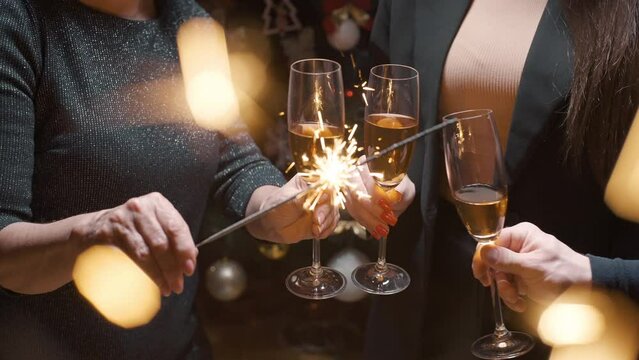 The family clinks glasses over the festive table, holds sparklers in their hands